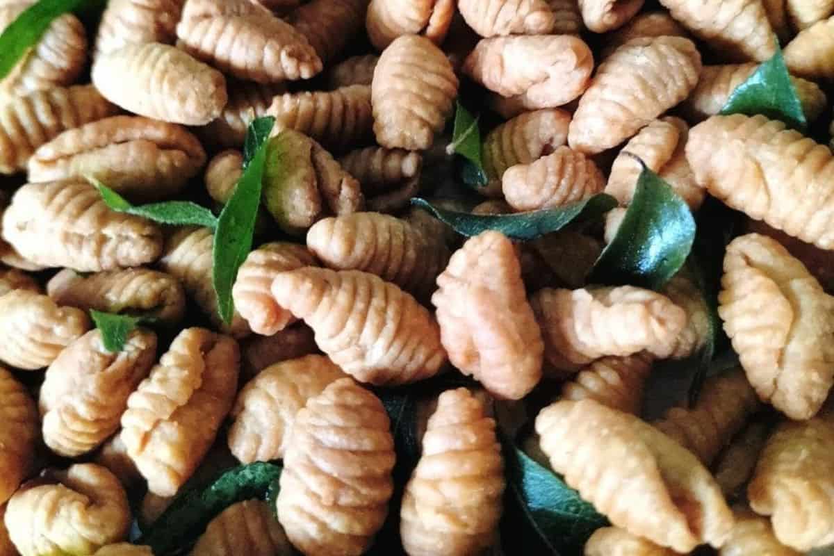 Kuih siput rangup berwarna keemasan dengan taburan daun kari