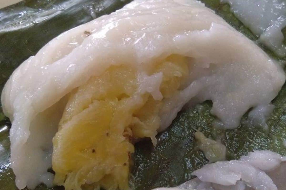 Nagasari berbungkus daun pisang, satu dibuka menampakkan seulas pisang di dalam adunan putih